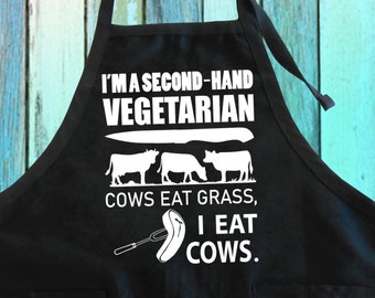 May include: Black kitchen apron with white text that reads "I'm a second-hand vegetarian. Cows eat grass, I eat cows."  The text is accompanied by a graphic of a cow and a knife.