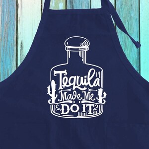 May include: Navy blue apron with a white graphic of a tequila bottle and the phrase "Tequila Made Me Do It." The apron features a bib and ties at the waist and neck, suitable for cooking or bartending.
