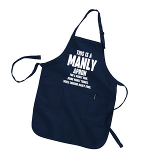 Puede incluir: Un delantal azul marino con un bolsillo blanco y el texto "THIS IS A MANLY APRON FOR A MANLY MAN, DOING MANLY THINGS, WHILE COOKING MANLY FOOD."
