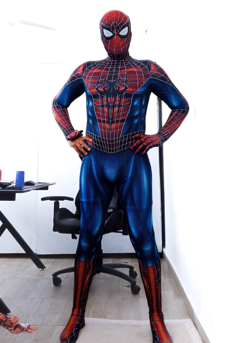 May include: A full-body Spider-Man costume in blue, red, and black. The suit features a web pattern across the red areas and a spider emblem on the chest. The mask covers the entire head, with white eye lenses.