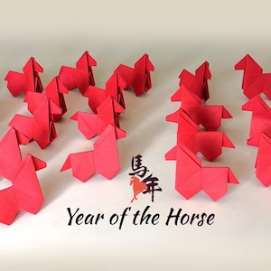 May include: A collection of red origami horses arranged on a white surface. The image includes the text "Year of the Horse" in black, along with Chinese characters. The horses are all folded from red paper.