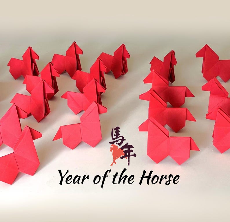 May include: A collection of red origami horses arranged on a white surface. The image includes the text "Year of the Horse" in black, along with Chinese characters. The horses are all folded from red paper.