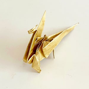 May include: A gold origami crane, a traditional Japanese paper folding art form.