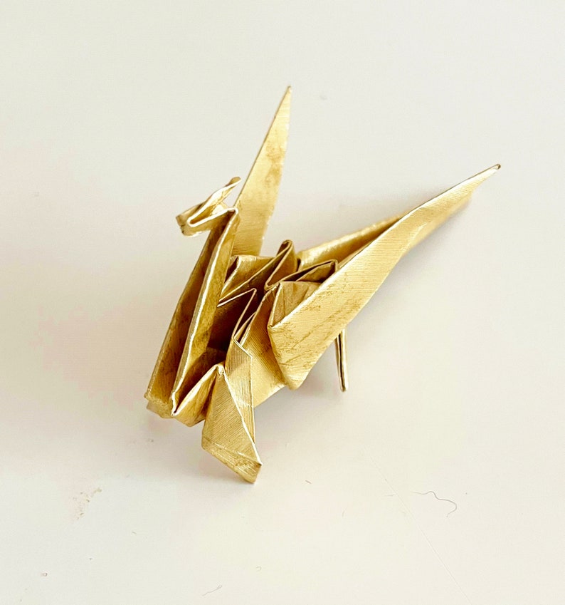 May include: A gold origami crane, a traditional Japanese paper folding art form.