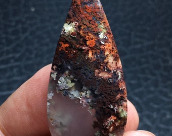 May include: A teardrop-shaped pendant made of agate with a brown, white, and green pattern. The agate has a translucent quality, allowing light to pass through it.