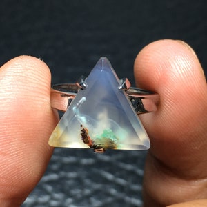 May include: A silver ring with a triangular shaped gemstone. The gemstone is clear with brown, green, and white inclusions.