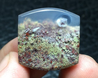 May include: A translucent, light green and red agate cabochon with a white, cloudy pattern. The stone has a smooth, polished surface.