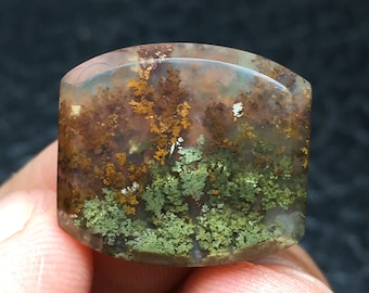 Könnte beinhalten: Ein durchscheinender, hellbrauner Achat-Cabochon mit grünen und braunen dendritischen Einschlüssen. Der Achat hat eine polierte, glatte Oberfläche.