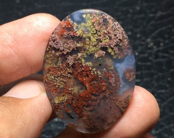May include: Oval shaped agate cabochon with a dendritic pattern in shades of brown, red, and white.