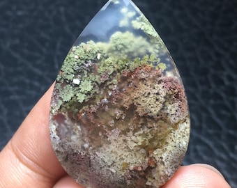 May include: A teardrop-shaped agate cabochon with a unique moss agate pattern. The stone features a mix of green, brown, and white colors, creating a natural, organic look.