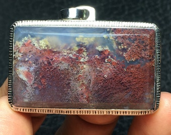 May include: A silver pendant with a rectangular agate stone featuring a swirling pattern of red, white, and brown colors.