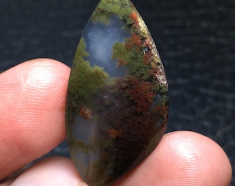 May include: A green, brown, and white agate cabochon with a unique, swirling pattern. The cabochon is shaped like a teardrop and has a smooth, polished surface.