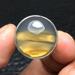 May include: A round, yellow and white agate gemstone set in a silver ring.