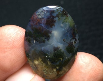 May include: A green, blue and brown agate cabochon with a cloudy, swirling pattern. The stone is oval shaped and polished.