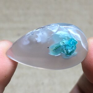 Peut inclure: Un cabochon en agate transparente en forme de larme avec un amas de cristaux bleu-vert &agrave; l'int&eacute;rieur.