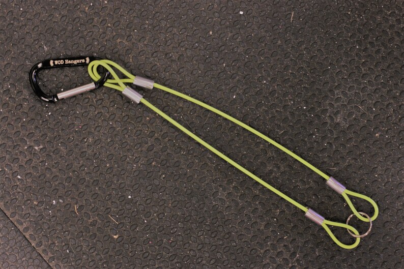 May include: A green exercise strap with a black carabiner clip and silver metal rings. The strap is labeled "WOD Rangers".