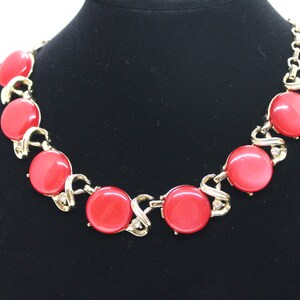 May include: A gold necklace with a series of large, round, red stones. The stones are connected by a gold chain with a twisted design.