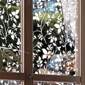 May include: A window film featuring a white, opaque, repeating botanical pattern of climbing vines and leaves applied to the glass panes. The design creates a semi-transparent effect, obscuring the view while allowing light to pass through.
