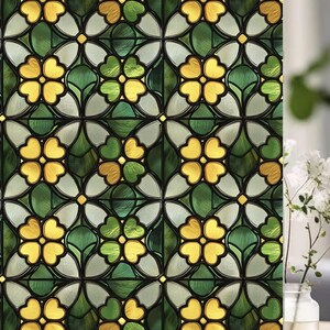 Op de afbeelding: Decoratieve raamfolie met een glas-in-lood effect. Het ontwerp heeft een herhalend patroon van gele en groene bloemvormen, tegen een achtergrond van heldere en donkergroene elementen. De folie is ontworpen om de uitstraling van traditioneel glas-in-lood na te bootsen.