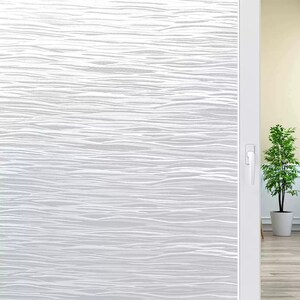 May include: White window film with a wavy, textured pattern. The film is applied to a sliding glass door, with a glimpse of a potted plant and a light-colored wall visible through the opening.