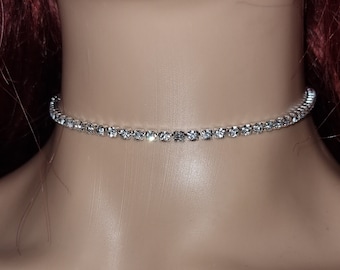 May include: A silver choker necklace with clear rhinestones. The necklace is shown on a mannequin's neck. The image also shows a close-up of the necklace in different lengths, ranging from 2.0 inches to 3.5 inches.