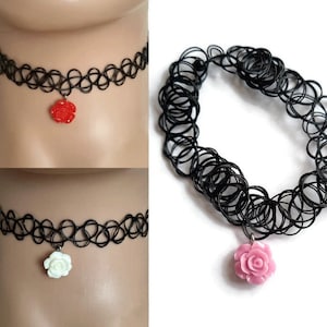 May include: Three black choker necklaces with a rose charm. The charms are red, white, and pink.