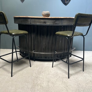 May include: Two black metal bar stools with green leather seats and a black metal bar counter with a wood top.