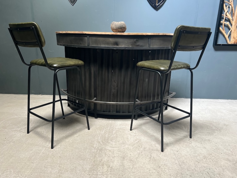 May include: Two black metal bar stools with green leather seats and a black metal bar counter with a wood top.