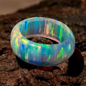 Puede incluir: Un anillo de &oacute;palo luminoso, que muestra un espectro de colores que incluye azules, verdes y amarillos. La superficie pulida del anillo refleja la luz, creando una exhibici&oacute;n cautivadora. La piedra preciosa est&aacute; engastada en una banda, ofreciendo un dise&ntilde;o moderno y elegante.