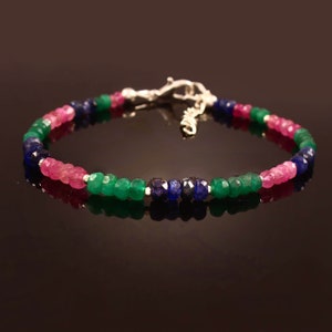 Könnte beinhalten: Ein silbernes Armband mit rosafarbenen, grünen und blauen Edelsteinperlen. Das Armband hat einen Karabinerverschluss.