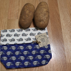 Könnte beinhalten: Eine wiederverwendbare Obst- und Gemüsetasche in Blau und Weiß mit einem Walmuster. Die Tasche hat ein braunes Etikett mit der Aufschrift "The Cotton Cabin Co."