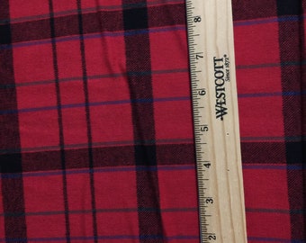 May include: Red and black plaid fabric with a ruler measuring 10 inches. The ruler is made of wood and has the words "Westcott Since 1872" printed on it.