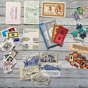 Könnte beinhalten: Eine Sammlung von Vintage-Spielteilen, darunter Geld, Karten und ein kleines Puzzle. Die Karten zeigen Bilder von Gebäuden und Text in Niederländisch. Das Geld ist in verschiedenen Stückelungen und Farben. Das Puzzle ist aus blauem Kunststoff.