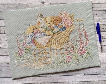 crossstitch bears in a pram, surrounded with flowers, dolls, a goose and a dog. fully completed work