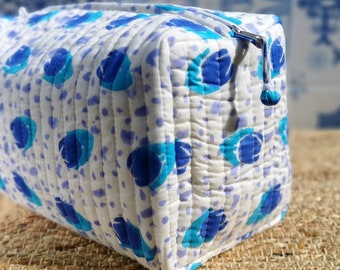 Pode incluir: Uma necessaire acolchoada branca com um padrão floral azul e turquesa. A necessaire tem um fecho de correr e uma aba de puxar.