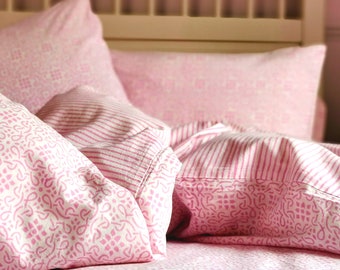 May include: A pink and white patterned bedding set with a striped pillow and a patterned pillow. The bedding is made of soft cotton and is perfect for a bedroom.