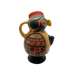 May include: A ceramic pitcher shaped like a rooster with a black, brown, yellow, red, and blue painted design. The pitcher has a spout and a handle.