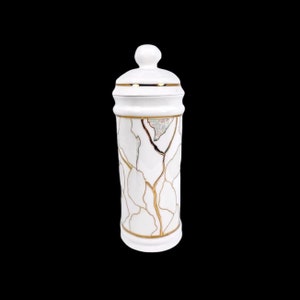 May include: White ceramic jar with a gold lid and a gold crackle design.