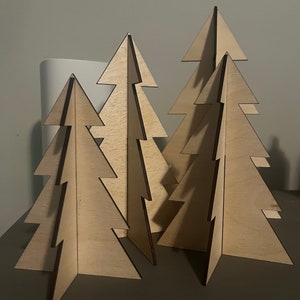 Puede incluir: Cuatro adornos de &aacute;rbol de Navidad de madera en varios tama&ntilde;os. Los &aacute;rboles est&aacute;n hechos de madera marr&oacute;n claro y tienen un dise&ntilde;o simple y minimalista.