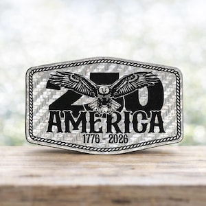 May include: A rectangular metal emblem with a silver and black design. The emblem features a spread-winged eagle above the word "AMERICA" and the numbers "1776-2026". The border has a rope-like design.