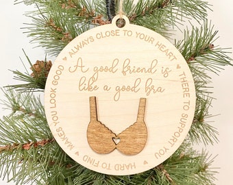 May include: A round wooden ornament with a brown bra cutout and the text "A good friend is like a good bra - Always close to your heart - There to support you - Hard to find - Makes you look good".