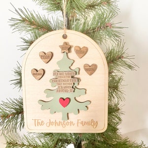 Peut inclure: Une d&eacute;coration de No&euml;l en bois en forme d'arbre de No&euml;l vert avec un c&oelig;ur rouge. L'ornement est personnalis&eacute; avec les noms Antonio, Cora, Olivia, Martin et le texte "Ce n'est pas ce qui se trouve sous le sapin de No&euml;l qui compte, mais qui est autour de lui." L'ornement comprend &eacute;galement l'ann&eacute;e 2023 et le texte "The Johnson Family."