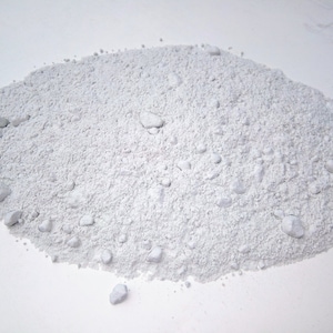 May include: A pile of white powder on a white surface. The powder is fine and granular, and it appears to be evenly distributed.