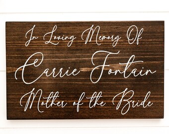 May include: A wooden sign with white text that reads "In Loving Memory Of Carrie Fontain Mother of the Bride".