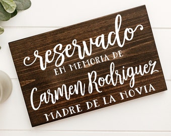 May include: A brown wooden sign with white text that reads "reservado en memoria de Carmen Rodriguez Madre de la Novia".