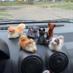 May include: Six small needle-felted cat figurines in various colors including orange, white, gray, black, and brown, arranged on a car dashboard. Two circular stickers with the text Cute Paw Shop are attached to the center console below the cats.