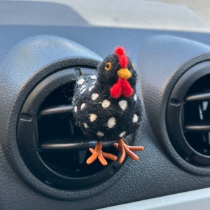 Puede incluir: Clip de ventilaci&oacute;n con forma de gallina con lunares blancos sobre fondo negro. Tiene cresta y barbilla rojas, pico amarillo y patas naranjas. Dise&ntilde;ado para sujetarse a la rejilla de ventilaci&oacute;n del coche.