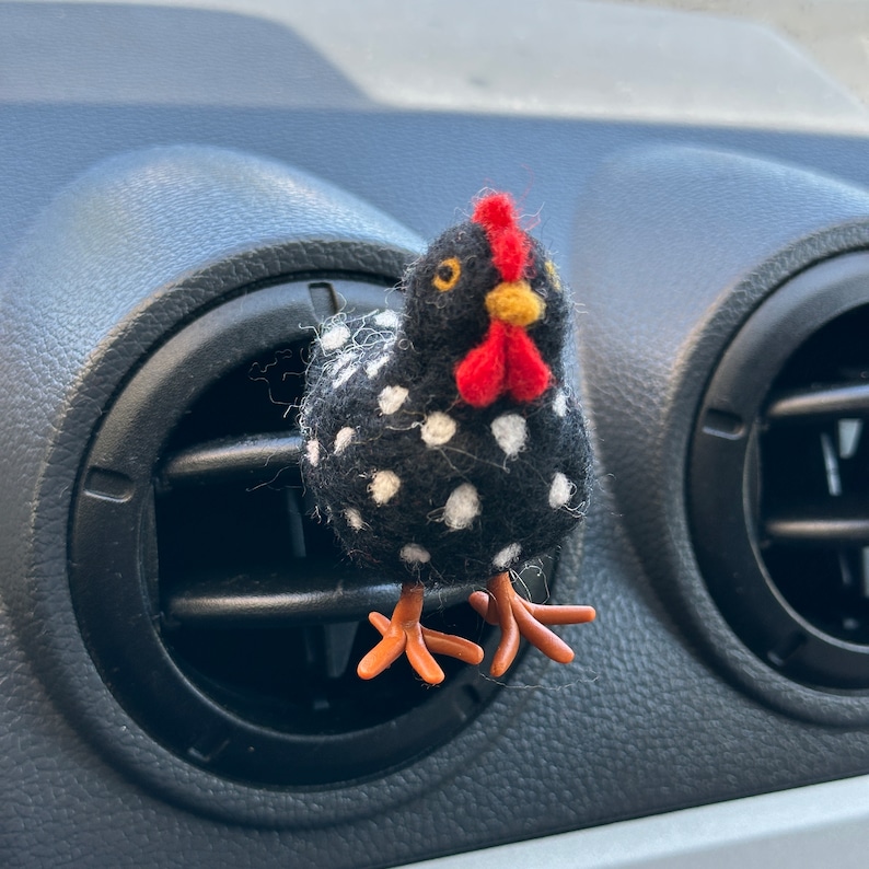 Puede incluir: Clip de ventilaci&oacute;n con forma de gallina con lunares blancos sobre fondo negro. Tiene cresta y barbilla rojas, pico amarillo y patas naranjas. Dise&ntilde;ado para sujetarse a la rejilla de ventilaci&oacute;n del coche.