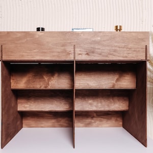 Peut inclure: &Eacute;tag&egrave;re en bois brun fonc&eacute; avec plusieurs compartiments et &eacute;tag&egrave;res. Le meuble est fabriqu&eacute; en bois teint&eacute;, mettant en valeur une couleur marron riche. La conception comprend une &eacute;tag&egrave;re sup&eacute;rieure avec trois petits objets et plusieurs &eacute;tag&egrave;res inf&eacute;rieures.