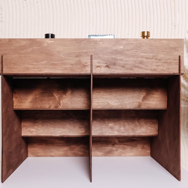 Peut inclure: &Eacute;tag&egrave;re en bois brun fonc&eacute; avec plusieurs compartiments et &eacute;tag&egrave;res. Le meuble est fabriqu&eacute; en bois teint&eacute;, mettant en valeur une couleur marron riche. La conception comprend une &eacute;tag&egrave;re sup&eacute;rieure avec trois petits objets et plusieurs &eacute;tag&egrave;res inf&eacute;rieures.